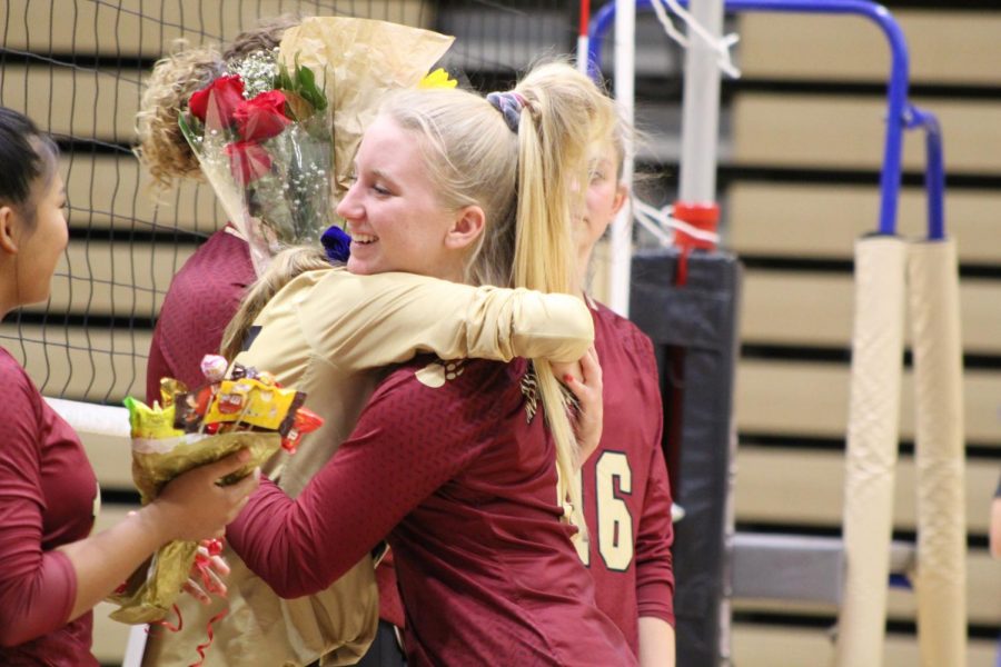 Volleyball player Jordan DeBlassio (12) hugs her teammates as she is recognized during senior night.