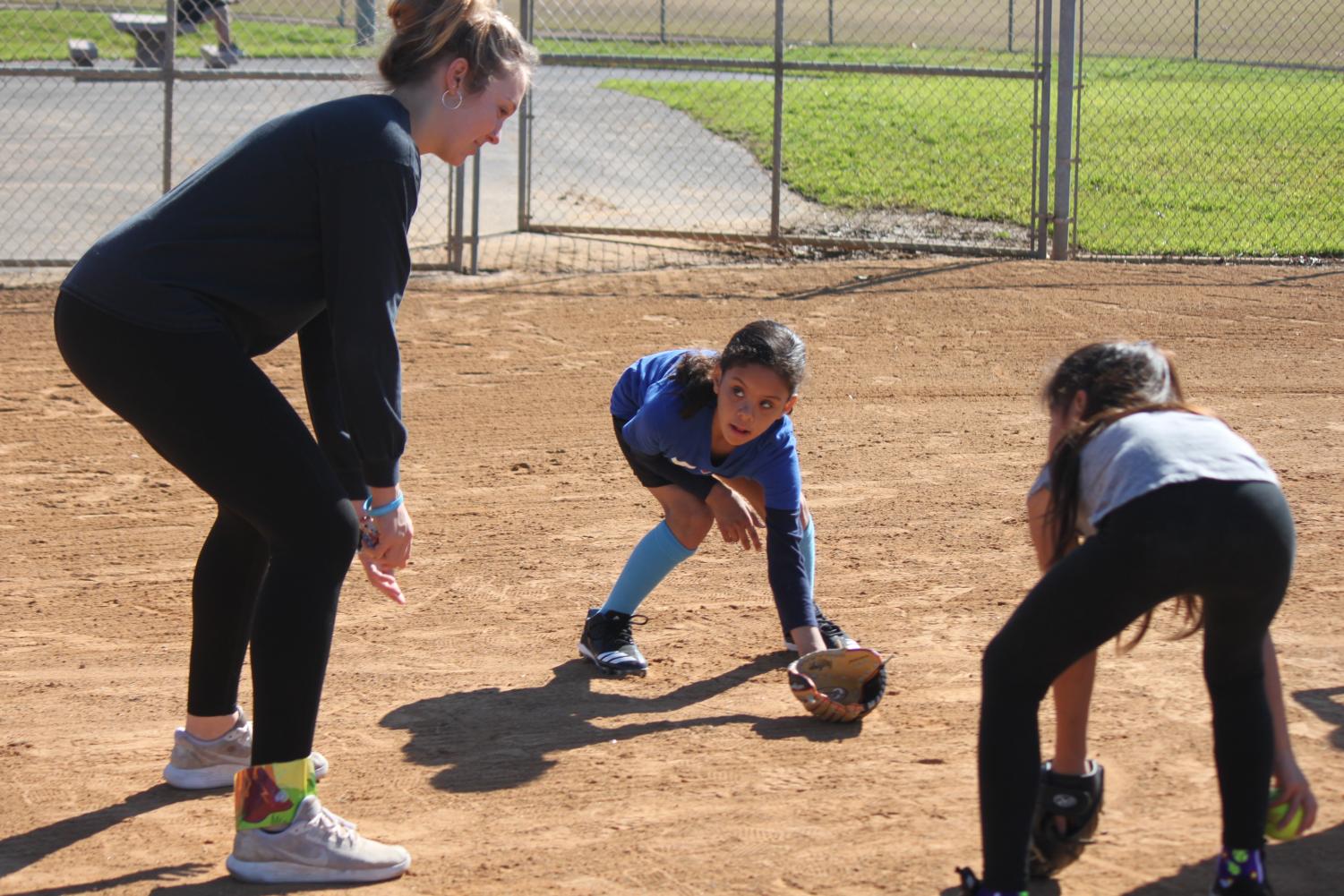 The+softball+team+volunteers+at+a+clinic+to+help+aspiring+young+players