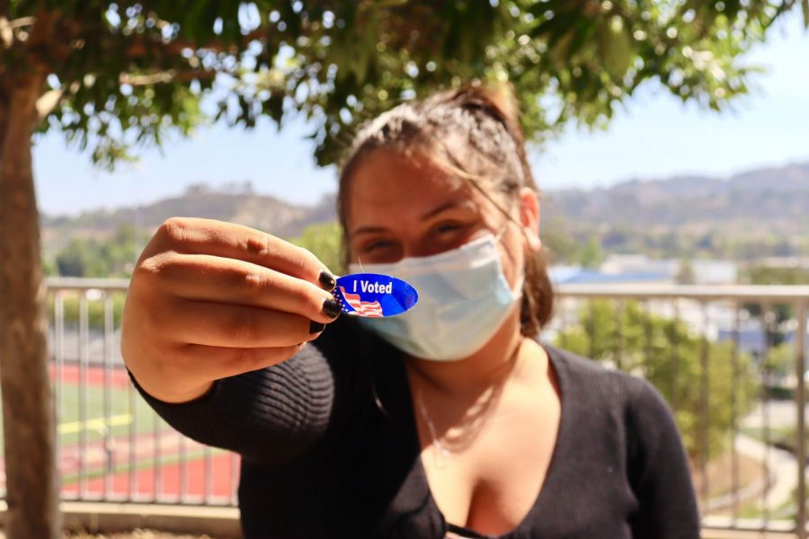 A student shows off the I Voted sticker voters receive after casting their ballot.