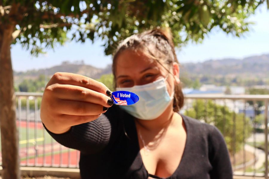 A+student+shows+off+the+I+Voted+sticker+voters+receive+after+casting+their+ballot.