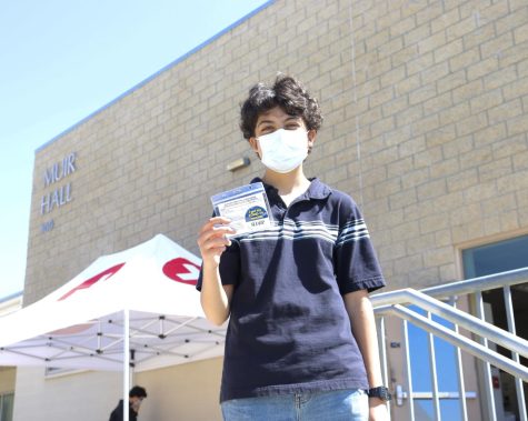 A student holds up their vaccination card