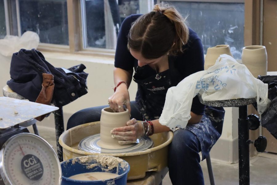 A ceramics student works on a pottery wheel in class.