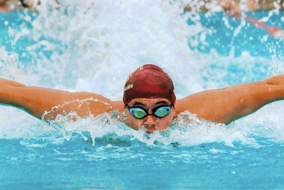Photo of Tyler Barris with a swim cap and goggles swimming.