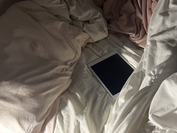 An iPad is being used late at night. The given student stayed up on their iPad instead of going to bed. When I go to bed, I tend to stay up on my phone a lot longer than I want to, said junior Maddy Donlon.